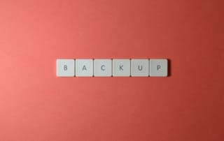 Free Close-up of keyboard keys spelling 'BACKUP' placed on a coral-colored surface. Stock Photo